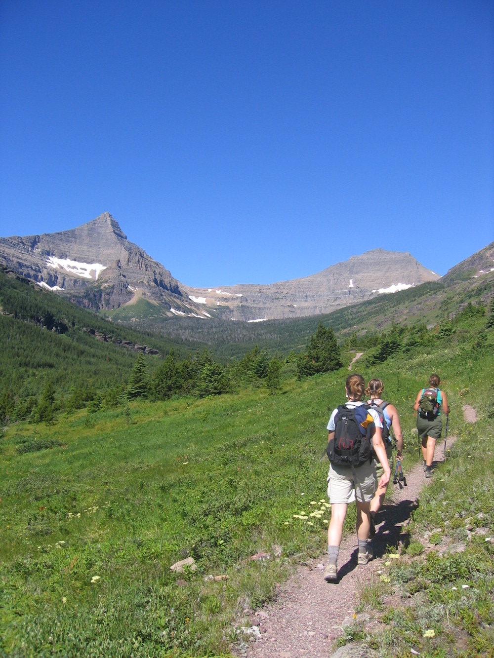 Happy hikers on the Dawson-Pitamakin Loop trail in the Two Medicine area of Glacier National Park, Montana. Flinsch Peak is to the left.